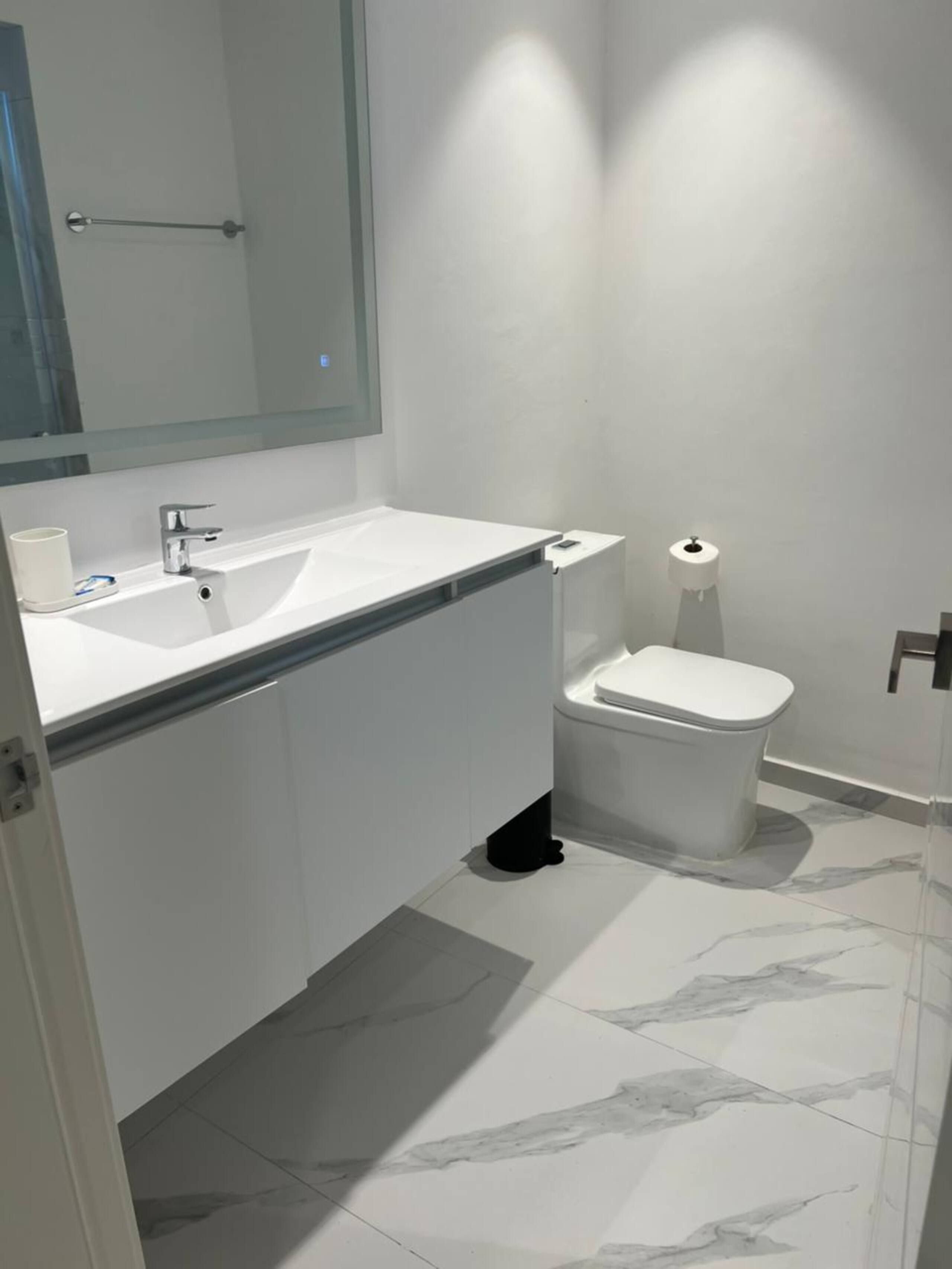 Baño moderno con lavabo y espejo retroiluminado