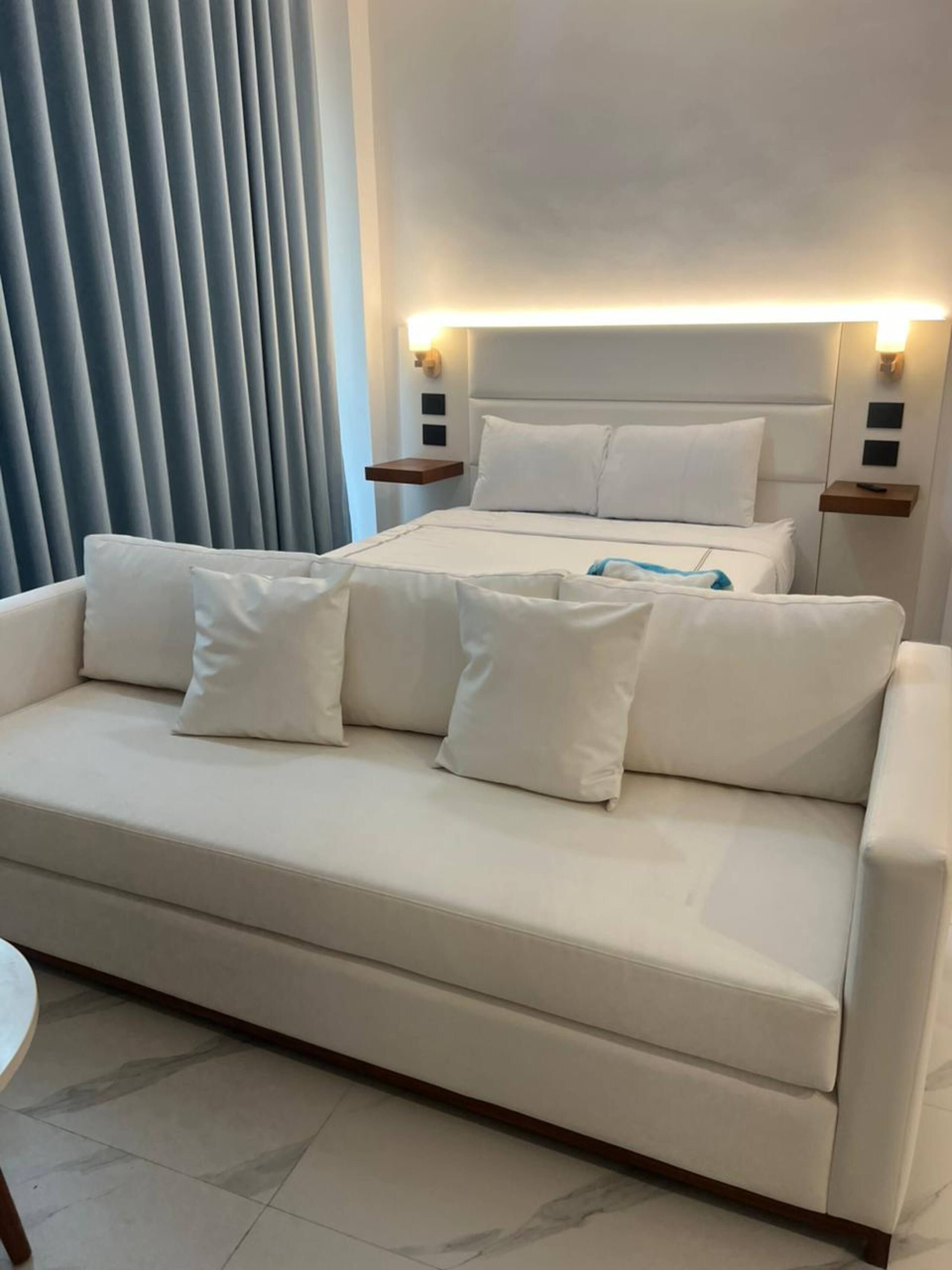 Suite con cama queen y sofá cama blanco