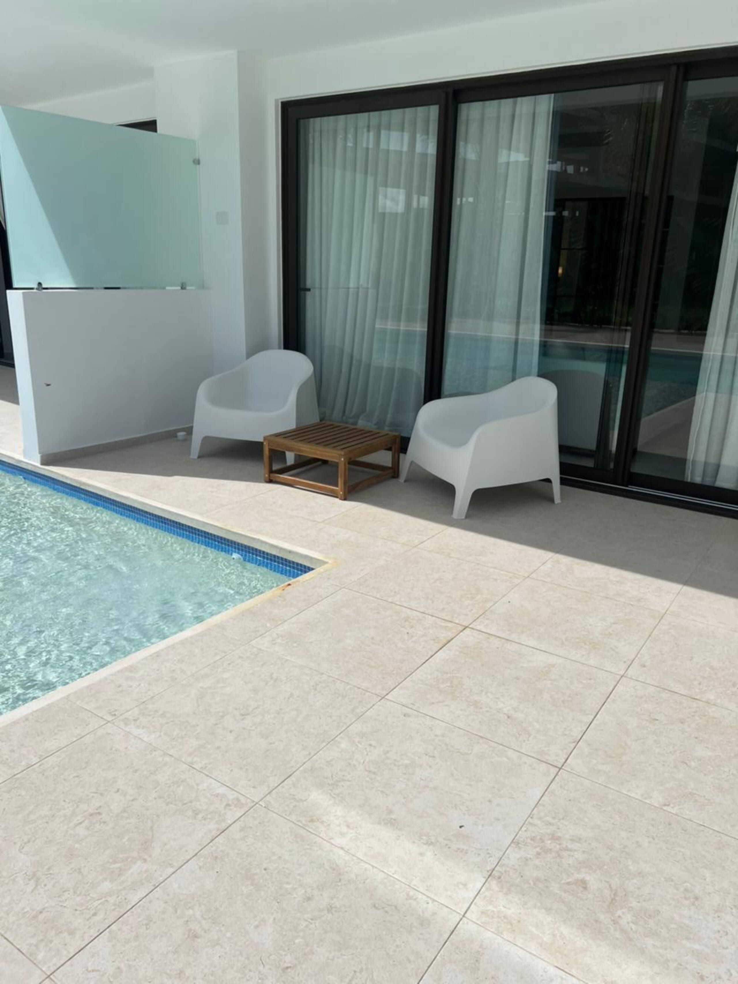 La terraza privada del apartamento con dos sillones; la piscina empieza en el borde de la terraza